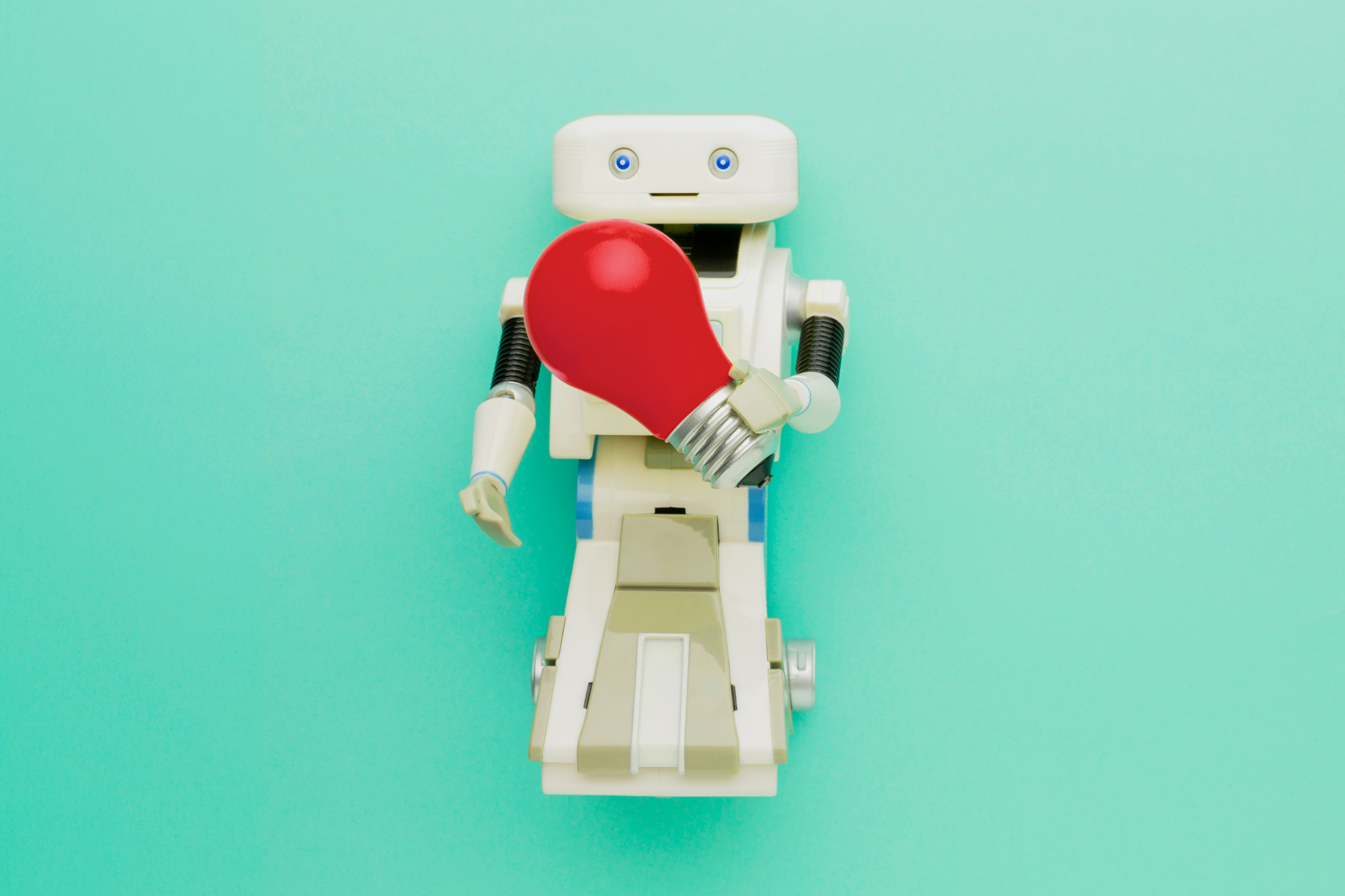 Robot con bombilla roja sobre fondo turquesa, símbolo del marketing en la era de la IA