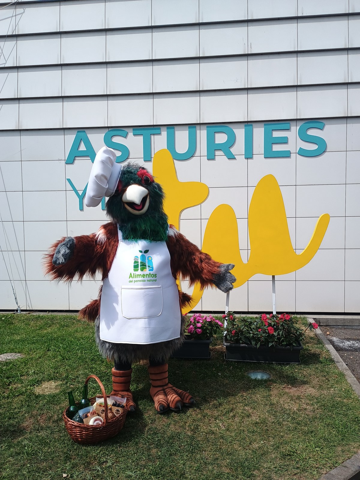 Comiḷḷón, mascota de Alimentos del Paraíso Natural, junto al logo Asturies Yes en la FIDMA